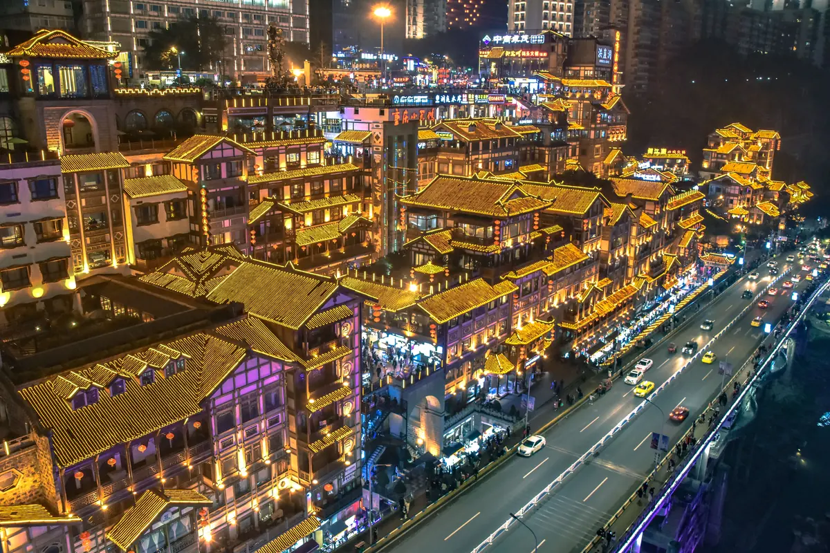 Vista aérea de los tejados dorados de Hongya Cave sobre una concurrida carretera en Chongqing de noche.