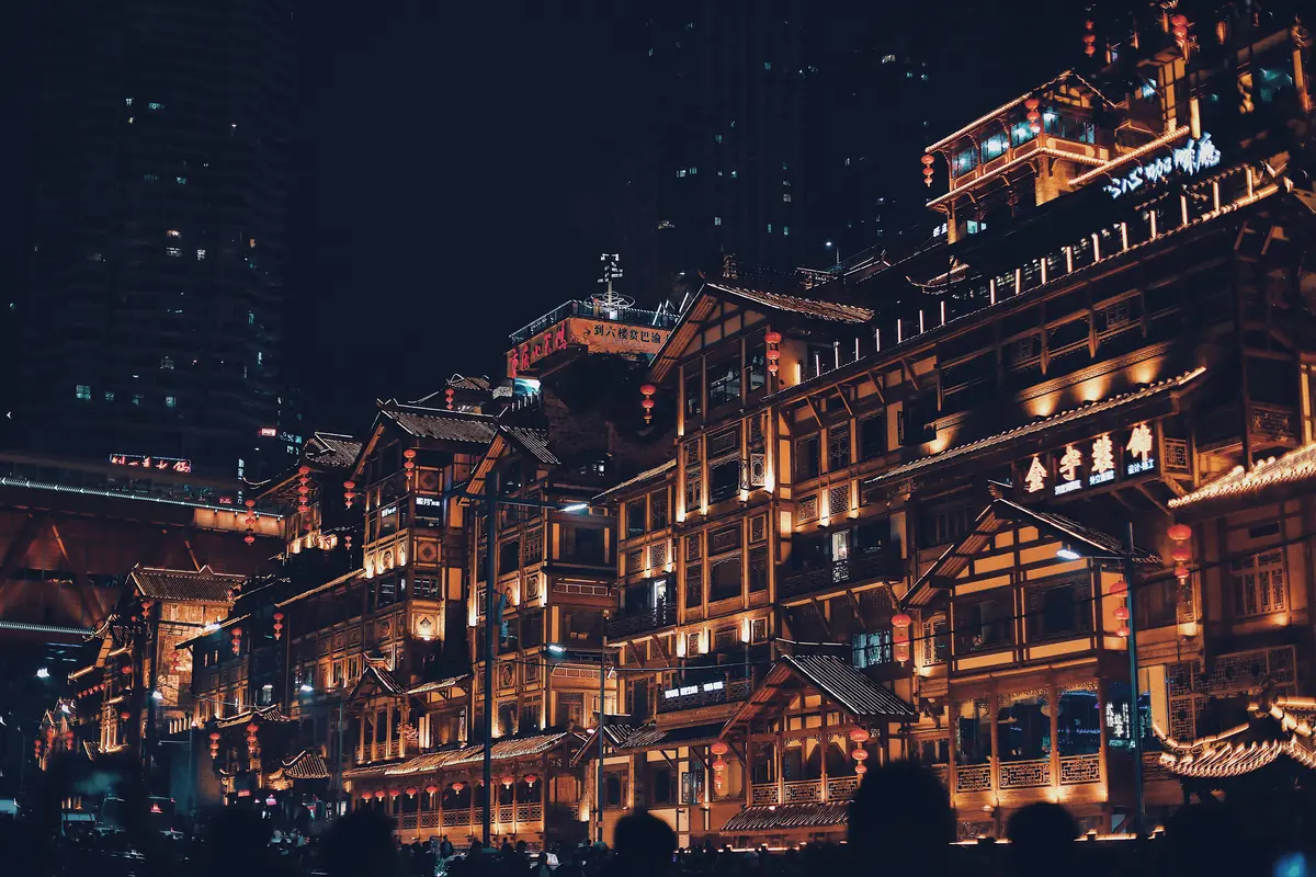 Hileras de edificios con fachadas de madera al estilo palafito resplandeciendo con luz cálida al atardecer en Chongqing.