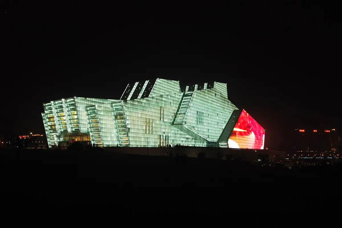 Das Chongqing Grand Theatre, ein großes Gebäude mit Glasfassade, nachts grün und rot beleuchtet